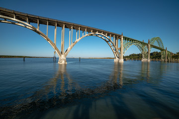 A side profile view of the Yaquina Bay Bridge  taken at sunrise during low tide in Newport Oregon in a horizontal view