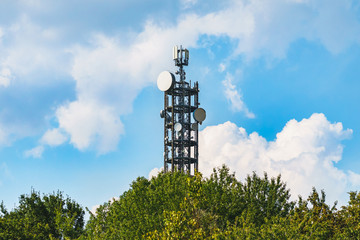 Funk und Radio Antenne hinter Bäumen und vor einem schönen leicht bewölktem Himmel