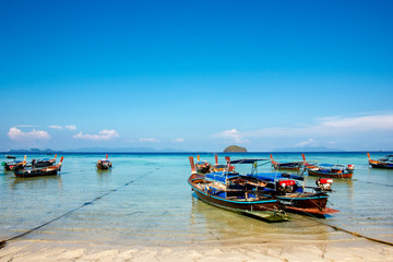 Fototapeta na wymiar Thai longtail boats that are parked at the beach in the sea, with blue sky in Thailand. Boat tour