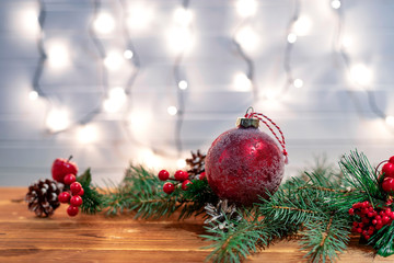Christmas decoration with spruce branches with a red ball and a garland. Winter holiday light decoration.