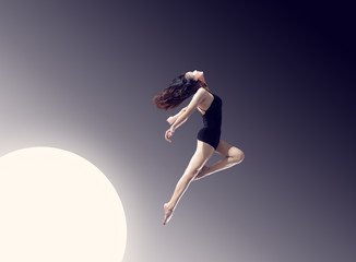 A long-legged girl jumping in front of a minimalist, graceful background