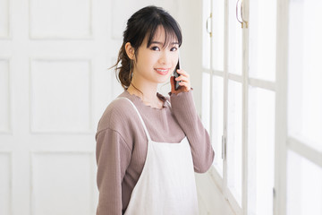 窓際でスマホを持つ若い女性