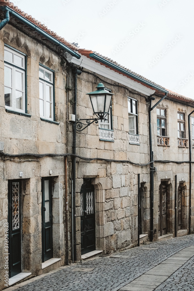 Poster Vertical shot of a street with antique stone buildings in Portugal