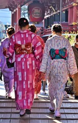 Naklejka premium Young Asian women wearing traditional kimonos walk towards a temple