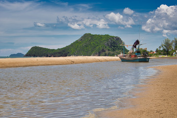 This unique photo shows a fishing boat running aground on the beach in Thailand and the Pak Nam Pran mountain range in the background
