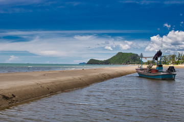 This unique photo shows a fishing boat running aground on the beach in Thailand and the Pak Nam Pran mountain range in the background