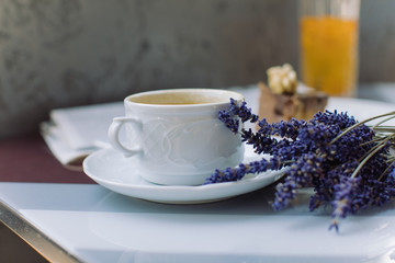 Cup of coffee, cream dessert, lavender bouquet, fresh newspaper on table. Romantic coffee break on summer terrace