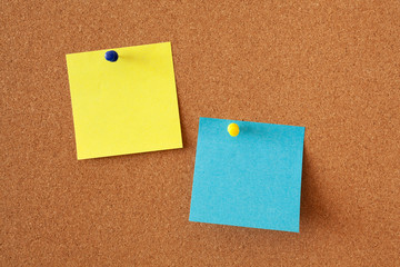 Yellow and blue sheets for notes on a corkboard. Office or business background.