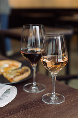 Close up of glass of red and rose wine with 4 cheese pizza and newspaper on background. Dating concept. Weekend couples leisure.