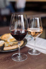 Close up of glass of red and rose wine with 4 cheese pizza and newspaper on background. Dating concept. Weekend couples leisure.