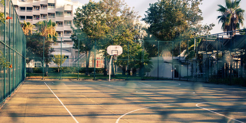 empty basketball court behind metal fence in early morning time