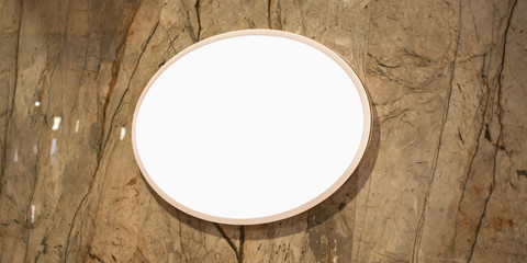 white blank circle display with mockup hanging on marble wall of fashion store