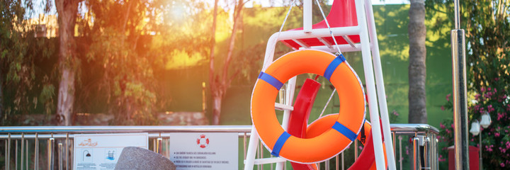 bright lifebuoy orange color hanging near swimming pool