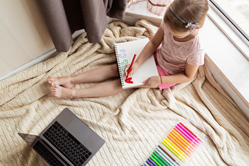 Little child learn english online at home. Homeschooling and distance education for kids. Caucasian Girl student drawing english letters at the notebook during coronavirus covid-19 quarantine