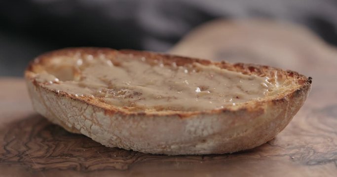 Slow motion man hand taker ciabatta slice with hazelnut spread closeup