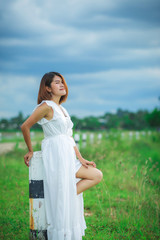 Beauty young woman outdoors enjoying nature. Woman in white dress in meadow with copy space
