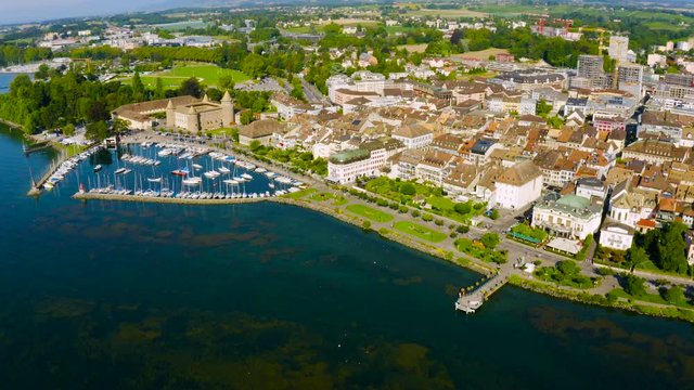 Morges Town On The Shores Of Lake Geneva With Moored Boats On The Harbor In Vaud, Switzerland - aerial drone (pullback)