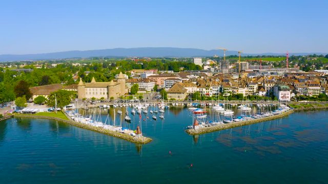 Boats At The Harbor Near The Waterfront Town Of Morges On The Shore Of Lake Geneva In Vaud, Switzerland - aerial drone (backward)
