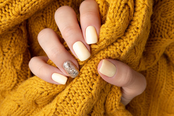 Manicured woman's hands with warm wool yellow sweater