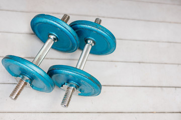 Fitness dumbbells, gym equipment. Two pairs of blue weights on wood floor background. Training workout at home concept