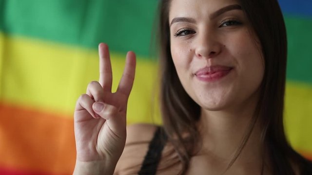 Beautiful lesbian woman gives peace victory gesture sign. LGBT pride concept