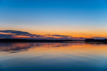 rays of the setting sun on the river bank