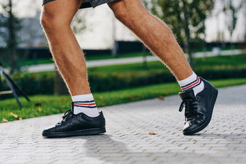 Legs in sneakers and black leggings running long distances in a park in nature