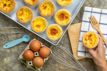 dessert egg tart or portugal egg tart sweet custard cream on wooden board and bright gray concrete background with eggs ingredient and cooking tools, top view