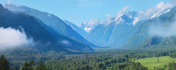 Summer in the Altai mountains, picturesque panoramic view. Snow on the peaks, green forests, blue sky.