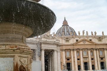 Piazza San Pietro in Rome, fountain with the dome and a detail of the church.
