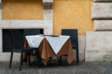 Rome, Italy, restaurant tables set in street outdoors against old building wall.