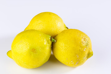 Drei frische gelbe Zitronen liegen auf einem weißen Hintergrund