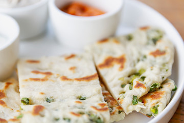 Flatbread with herbs on a plate with sauces. An appetizing snack. Close-up.