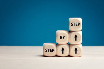 The word step by step on wooden cubes. Achievement or progress in business or career.