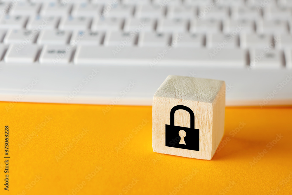 Poster padlock symbol on wooden cube against computer keyboard background. data protection or cyber securit