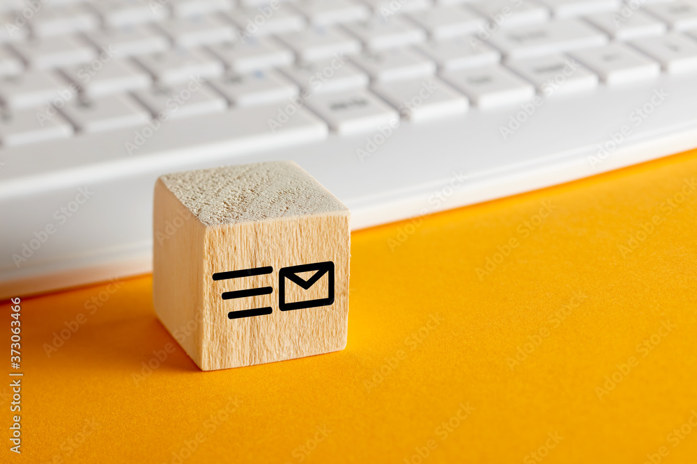 Poster email symbol on wooden block with computer keyboard background on yellow. customer care or e-mail me