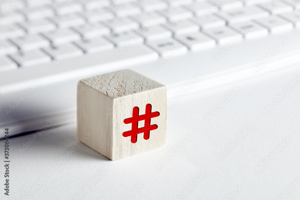 Poster hashtag symbol on a wooden cube with computer keyboard background on white