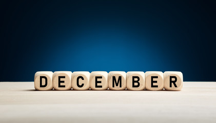 The month December written on wooden cubes against blue winter background with copy space. Month of the year.