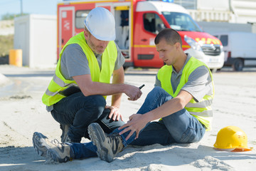 young construction worker on site with injured ankle