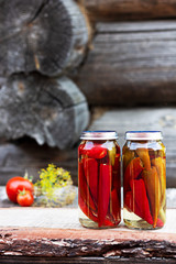 Chili peppers in a glass jar on a wooden table, homemade pickles