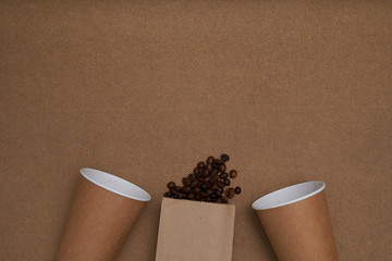 Two craft glasses with package and coffee beans on craft background . Monochrome photo Copy space - obrazy, fototapety, plakaty