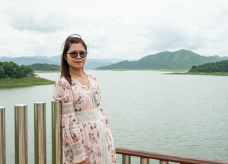 Asian woman Stand on the reservoir background at tourist places in thailand.