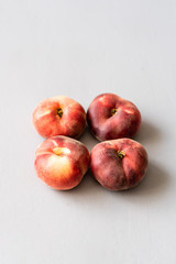 Vier flache rote Pfirsiche auf einemm grauen Hintergrund. Mitte, reif, gesunde Ernährung, Sommer.