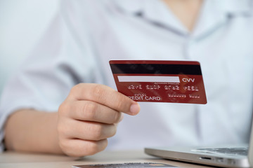Businesswoman hand hold credit card to online shopping on laptop computer from home, payment e-commerce, internet banking, spending money