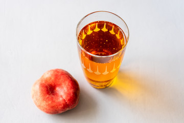 Ein Glas mit Eistee und ein frischer roter Pfirsich auf einem grauen Hintergrund. Nahaufnahme, Sommer, alkoholfrei.