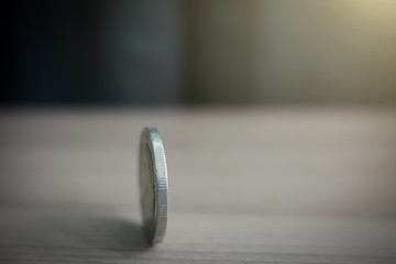 coins always have 2 side idiom idea concept, a Thai coin rolling on table with blurred background sunshine strong ligthing