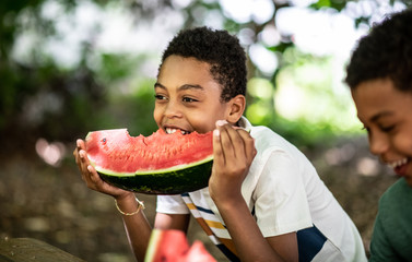 Side image of a boy eats a watermelon in nature on a sunny day