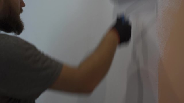 Man paint a wall at home in night time. White paint