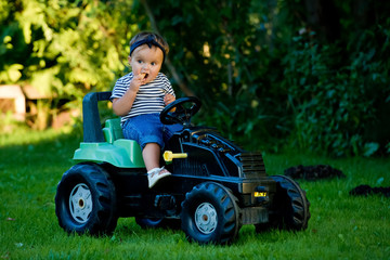 Baby girl playing with toy tractor in a garden.