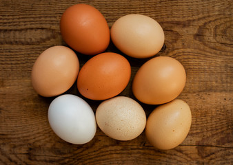 Rustic multicolored fresh eggs on a wooden background. Food background, top view.